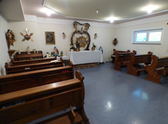 Einblick in die Kapelle mit Bänken und Altar
