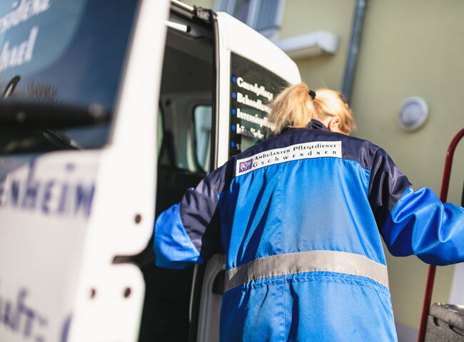 Eine Mitarbeiterin lädt Transportboxen aus dem Firmenwagen