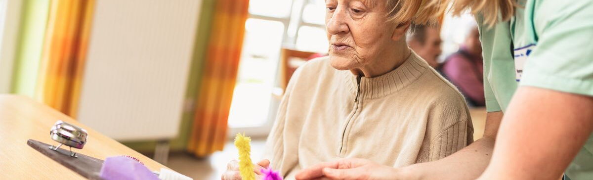 Eine Mitarbeiterin übt mit einer Bewohnerin an einem Motorikbrett