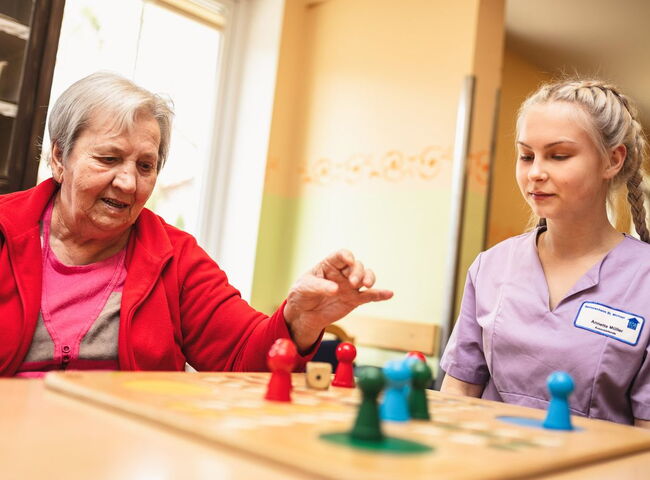Pflegepersonal spielt mit einer Bewohnerin Mensch ärgere dich nicht