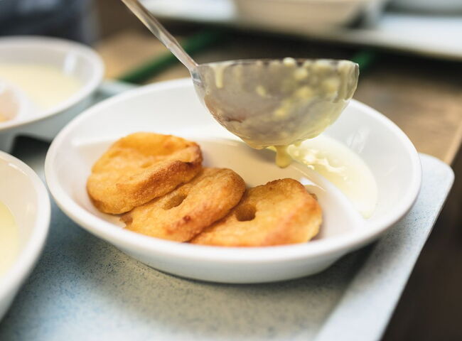 Vanillesoße wird zu Apfelkücheln portioniert