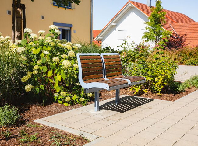 Eine Sitzbank vor Sträuchern