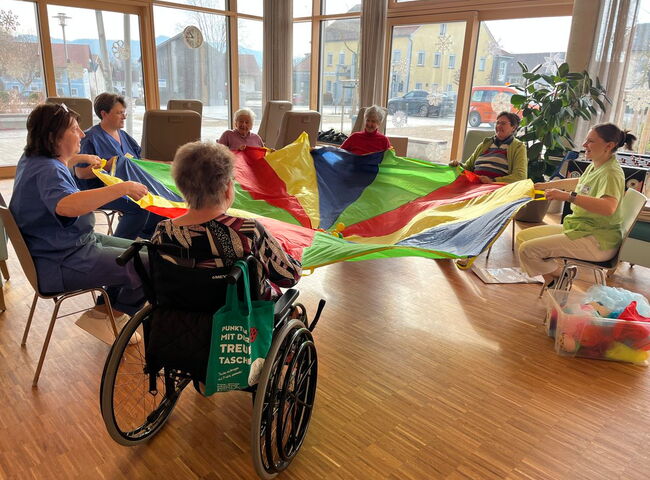 Bewohnerinnen sind mit einem Schwungtuch beschäftigt