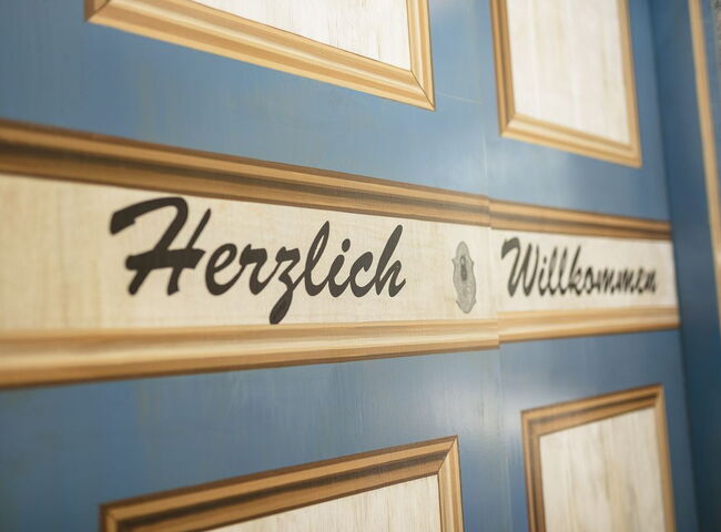 Künstlerisch gestaltete Aufzugtüre mit Aufschrift Herzlich Willkommen